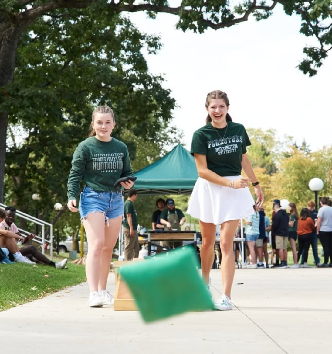 Two girls playing corn hole at an event